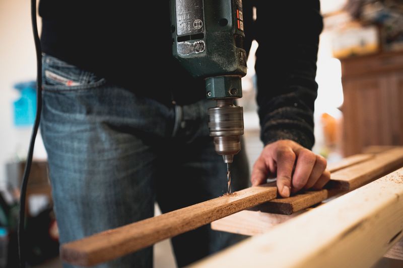 Formones y escoplo sobre un banco de trabajo junto a una pieza de madera con marcas de trazado